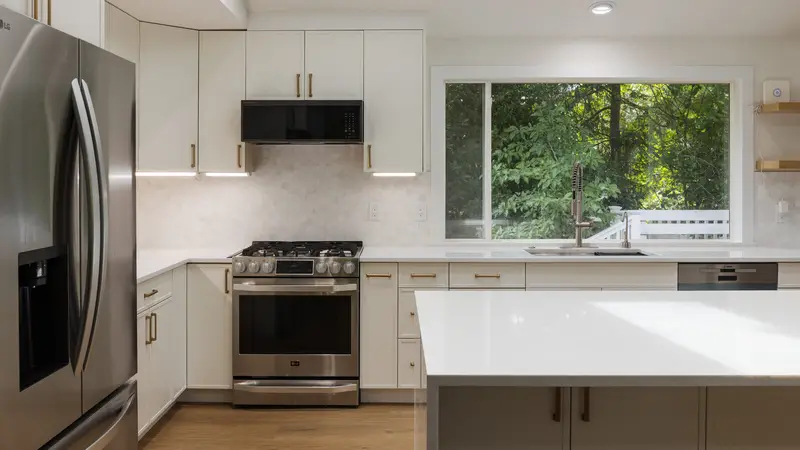 Remodelled kitchen with white cabinetry, quartz counters and gold fixtures